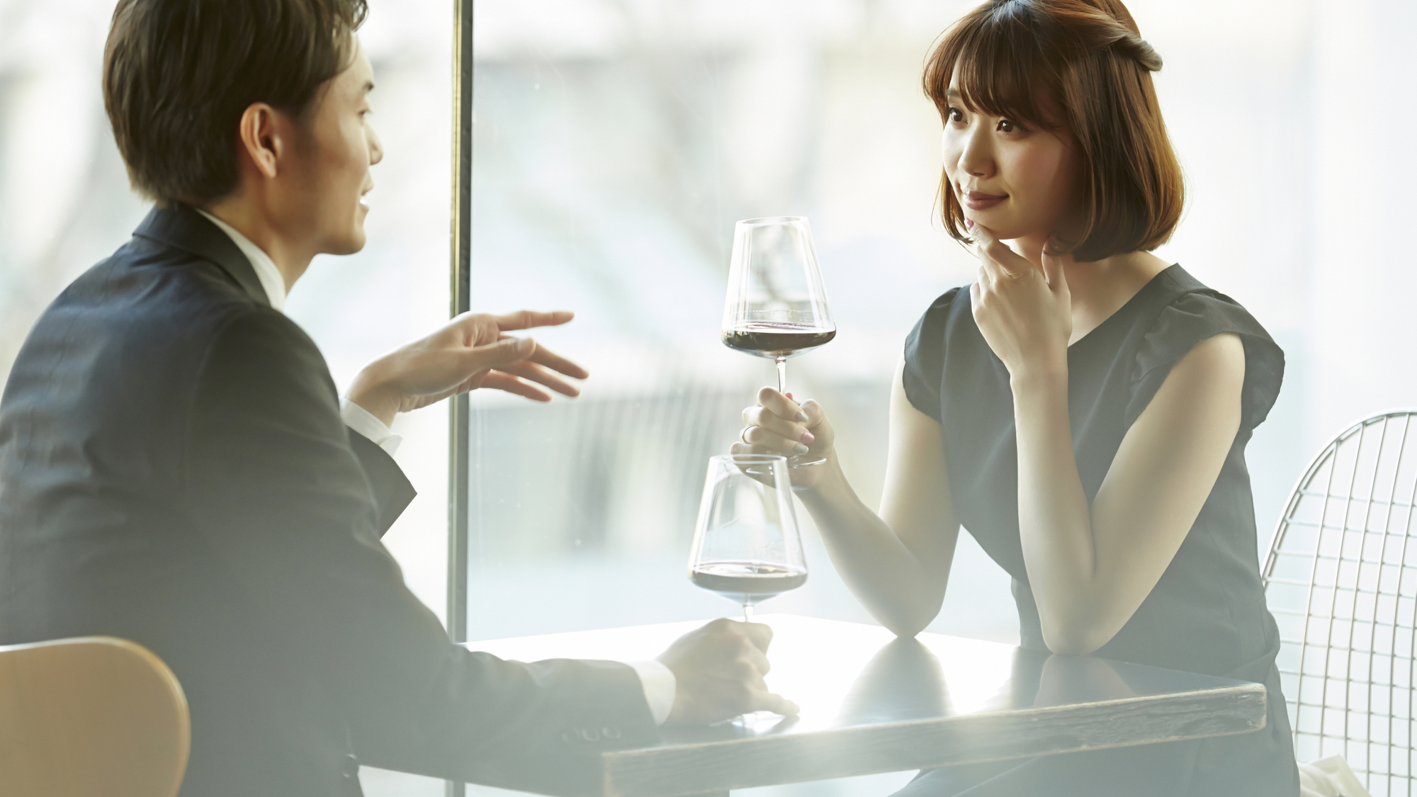 明るい店内でグラスを片手に会話を楽しむ男女